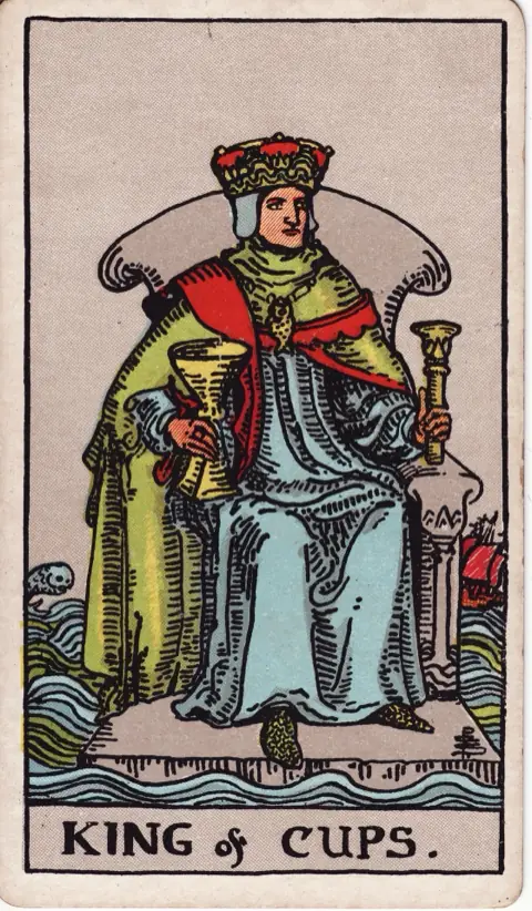 King of Cups, from the 1909 Rider-Waite-Smith deck: a king sits on a stone throne floating on a rough sea, holding a cup and a sceptre, a ship and a leaping fish behind him.