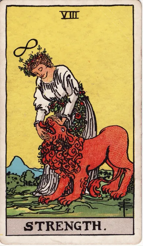 Strength, from the 1909 Rider-Waite-Smith deck: a woman in white with an infinity sign above her head gently closes the jaws of a lion, a chain of flowers around her waist and the lion’s neck.
