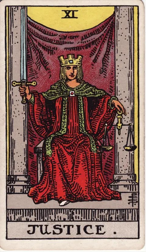 Justice, from the 1909 Rider-Waite-Smith deck: a crowned figure in a red robe sits between two pillars, holding an upright sword in the right hand and a pair of scales in the left.