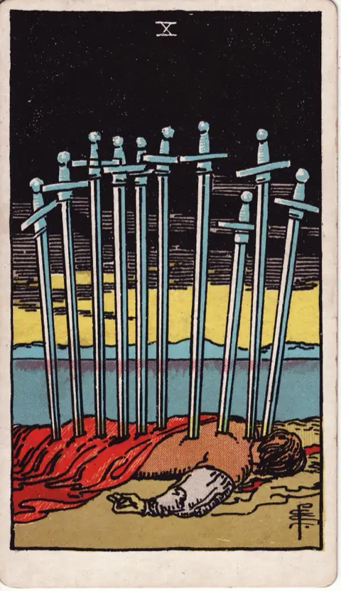Ten of Swords, from the 1909 Rider-Waite-Smith deck: a man lies face down on the ground with ten swords in his back under a black sky, a yellow dawn over the water.