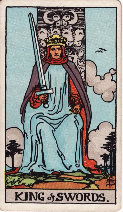 King of Swords, from the 1909 Rider-Waite-Smith deck: a king sits facing forward on a throne carved with butterflies and crescent moons, holding an upright sword.