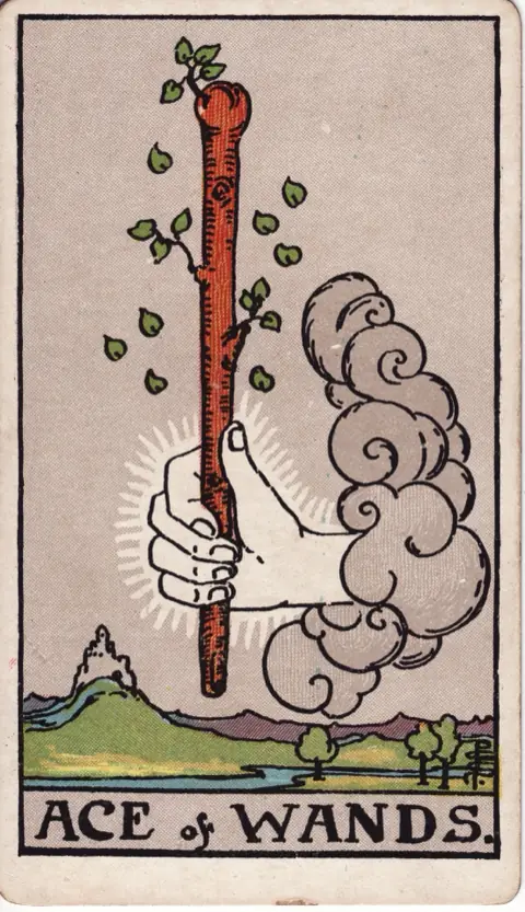 Ace of Wands, from the 1909 Rider-Waite-Smith deck: a hand comes out of a cloud holding a sprouting wooden wand, a castle on a hill and a river in the land below.