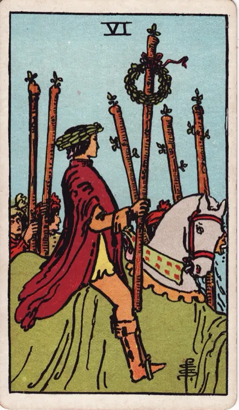 Six of Wands, from the 1909 Rider-Waite-Smith deck: a man wearing a laurel wreath rides a white horse through a crowd, holding a wand tied with another wreath, people with wands walking beside him.