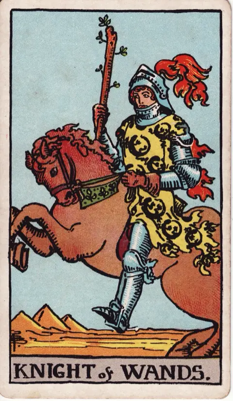Knight of Wands, from the 1909 Rider-Waite-Smith deck: a knight in a tunic patterned with salamanders rides a rearing horse across the desert, holding a sprouting wand, pyramids behind him.