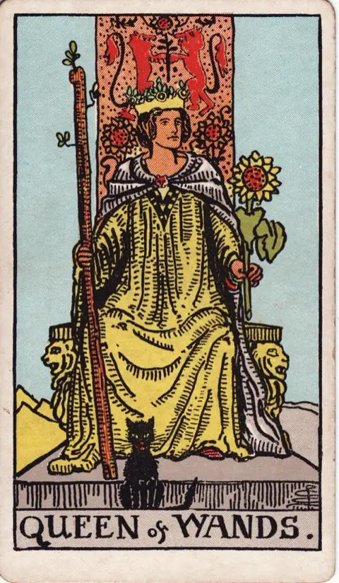 Queen of Wands, from the 1909 Rider-Waite-Smith deck: a queen sits on a throne carved with lions, holding a sprouting wand and a sunflower, a black cat sitting at her feet.